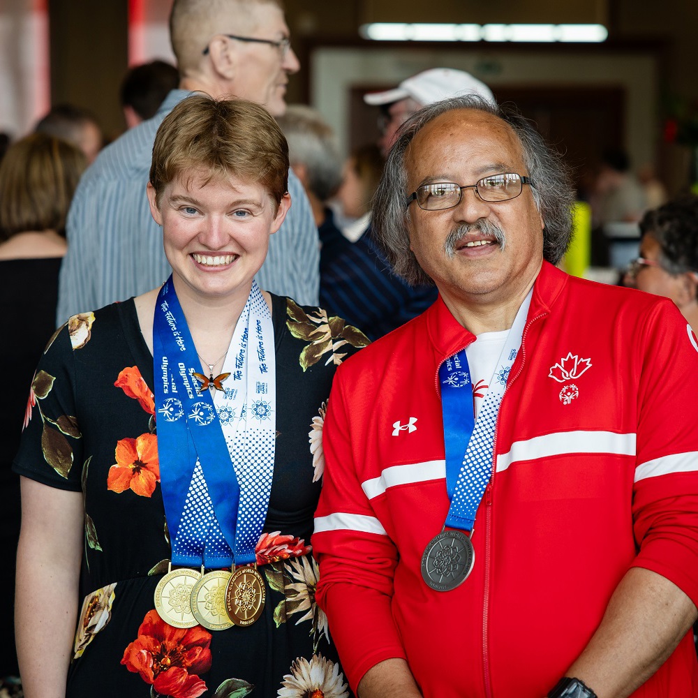 Two Special Olympics athletes standing while wearing medals
