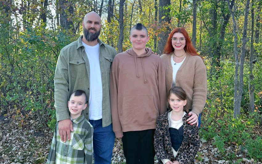 The Von Doelln family posing together on a trail in front of a forested area. 