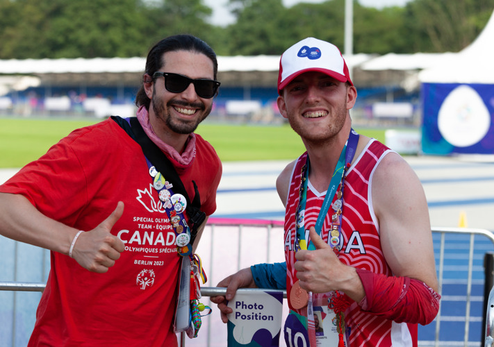 Two men smiling at the camera and giving thumbs up.