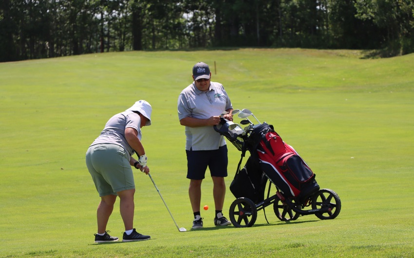 Team PEI 2026 Golf athlete, Heidi Mallett, taking a shot with Coach / Caddie watching