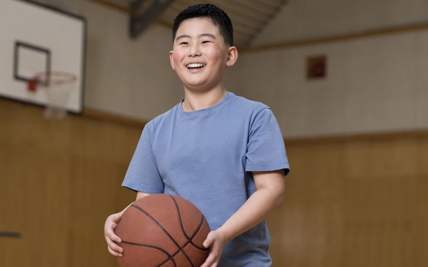 Young boy in blue shirt holding a basketball