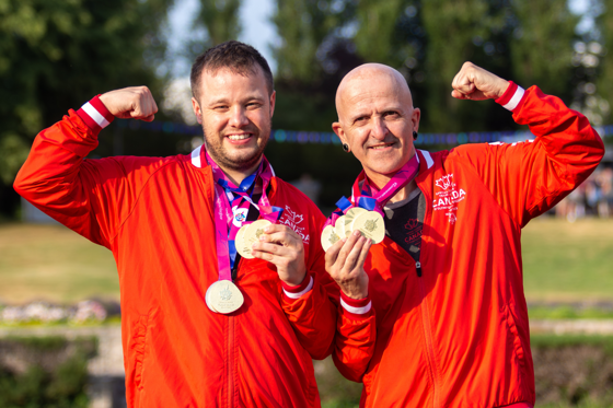 Two athletes in Team Canada uniforms with medals around their necks. 