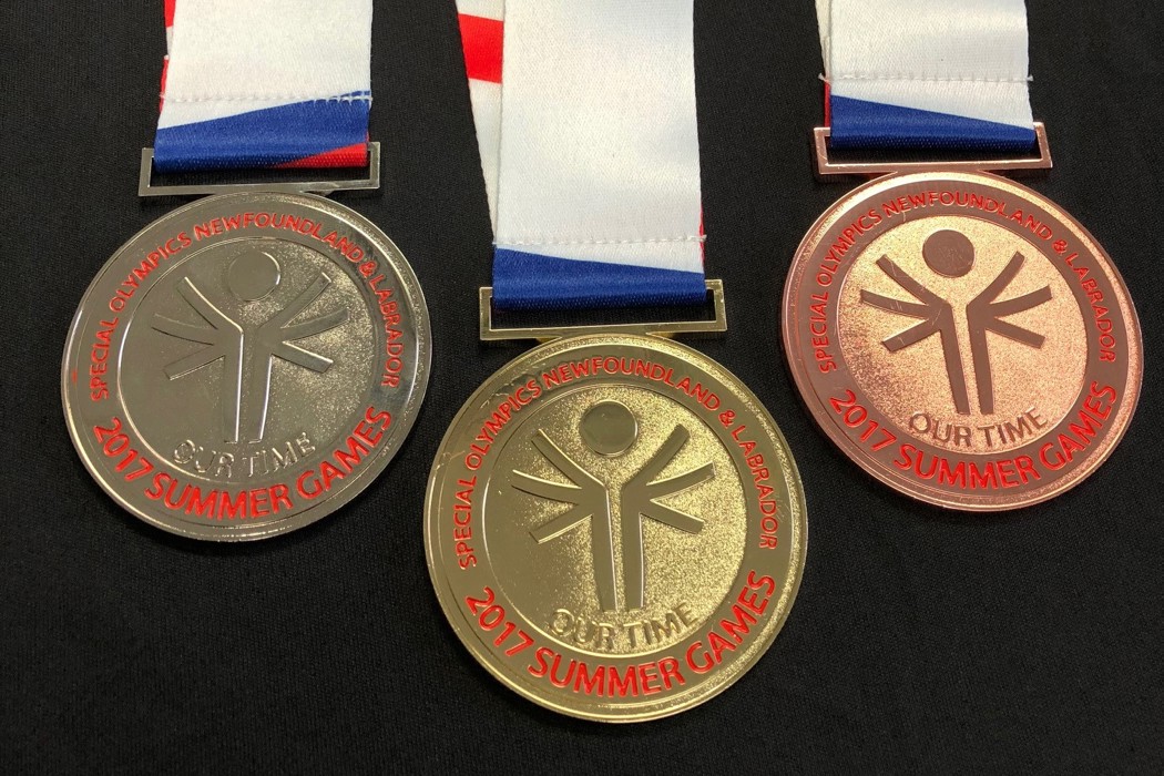 Three Special Olympics Newfoundland & Labrador medals on a black background. From left to right is a silver, gold, and bronze medal. The medals have the Special Olympics logo on it, and it reads "2017 Summer Games".