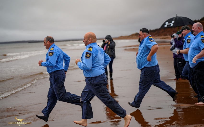 A group of people run into the water on the beach for a Polar Plunge event