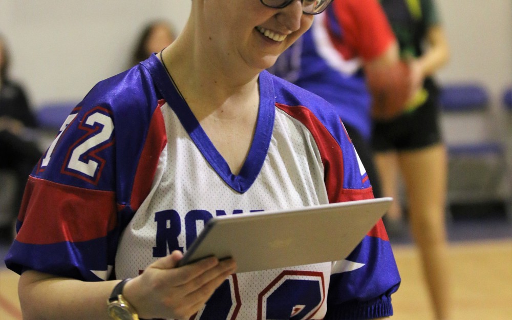 A closeup image of a volunteer holding an iPad. She is smiling and looking down.