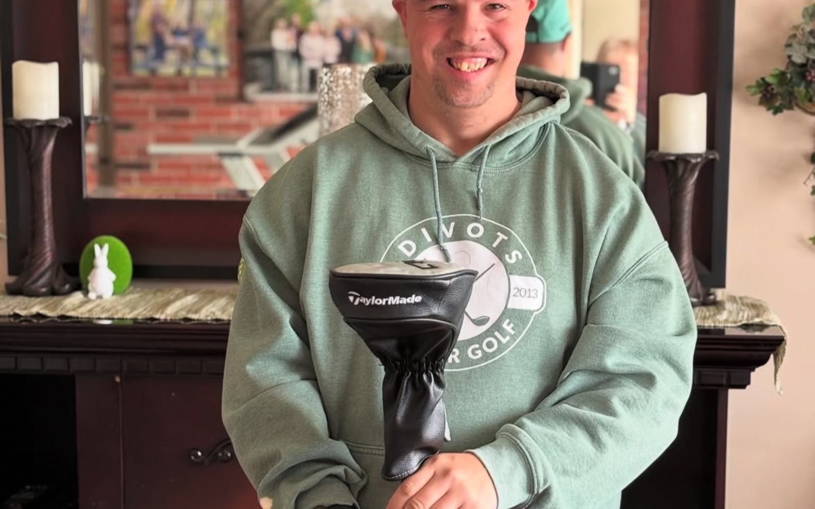Man in a green taylor made golf hat holding a driver. 