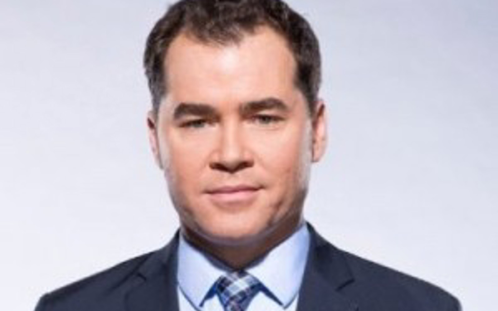 Homme en costume bleu, chemise bleu clair et cravate à carreaux bleus.