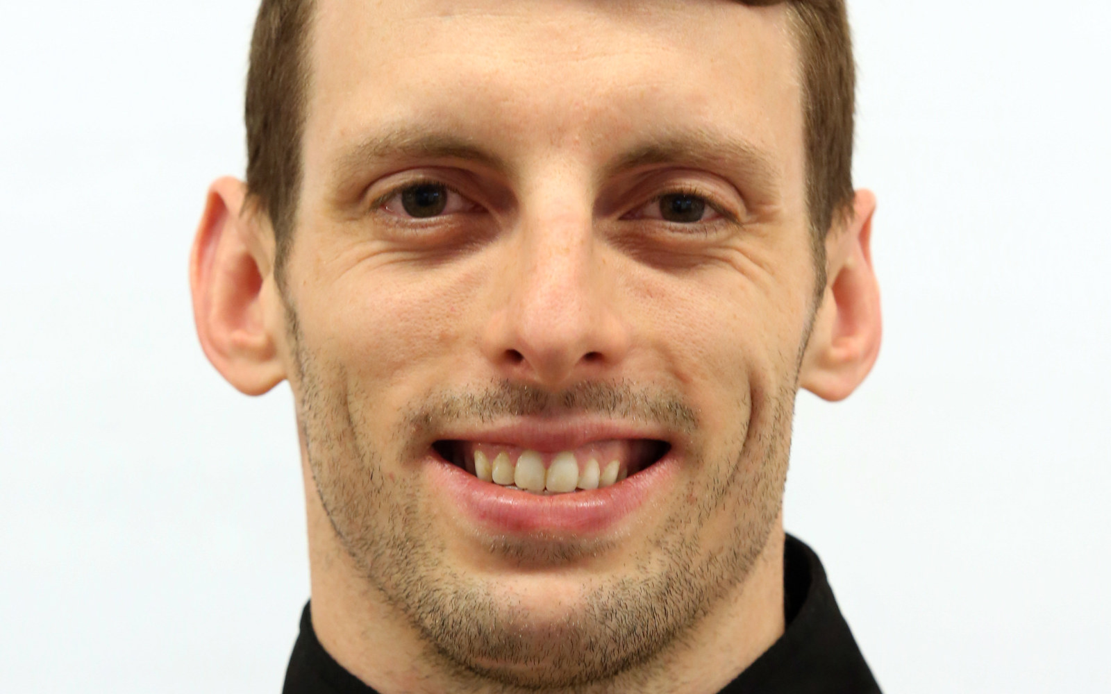 Headshot of a man in a black zip up. 