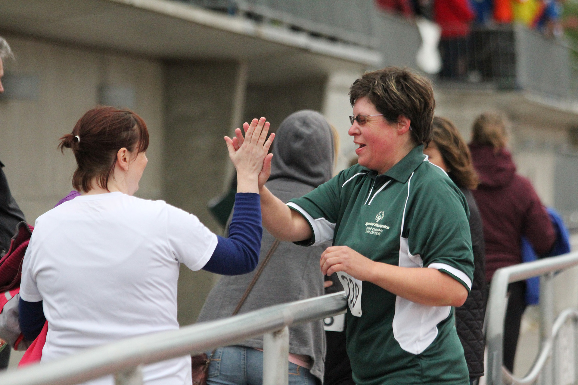 Special Olympics BC athlete high fives a fellow athlete after their race.