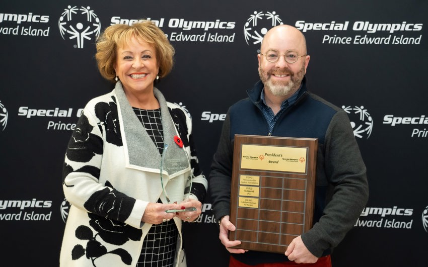 Volunteer Betty Anne is recognized at Special Olympics PEI's Annual Awards; 2 people standing in front of Special Olympics PEI's backdrop