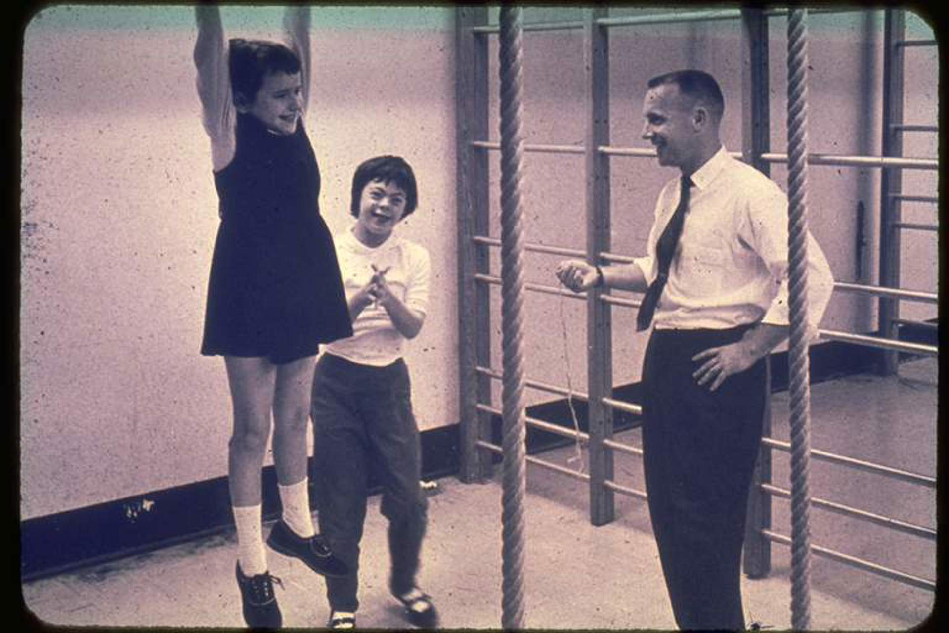 Two young children playing while a man in a suit stands beside them