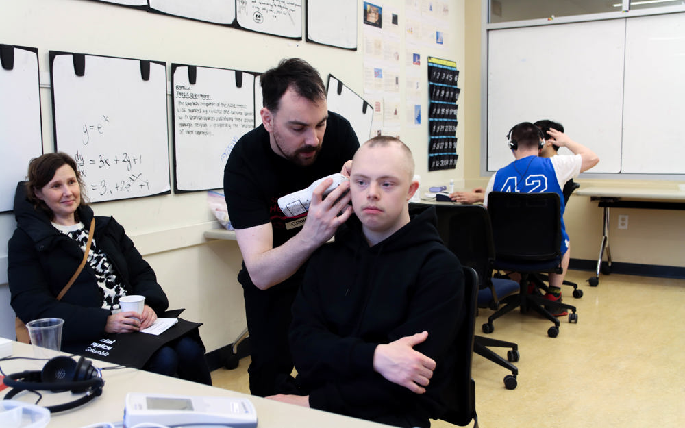 An athlete gets his ears checked by a volunteer.
