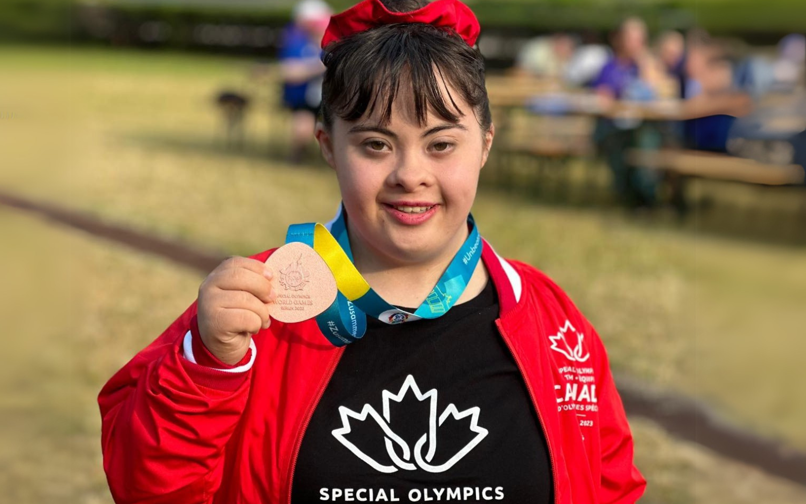 Un athlète vêtu de l'uniforme de l'équipe canadienne, une médaille autour du cou.