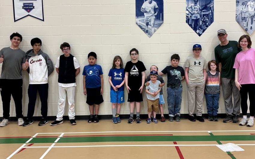 A group of youth softball athletes and volunteers standing in a gym