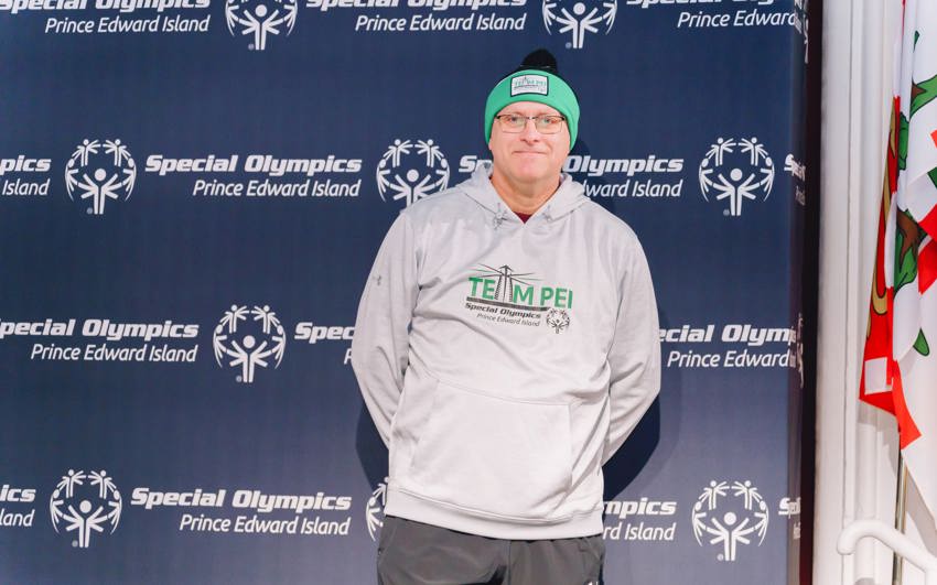 A Team PEI Volunteer standing at a photo backdrop