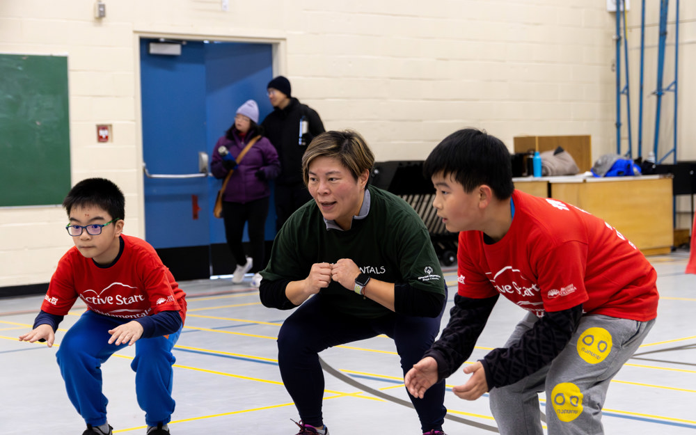 Two young boys with intellectual disabilities join their coach in warm-up exercises.