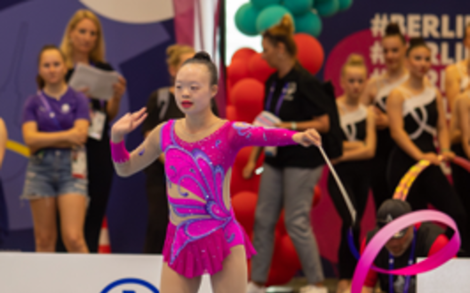 Girl in a purple bodysuit with a rhythmic gymnastics baton.