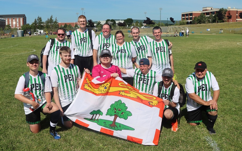 Team PEI 2026 Soccer standing together and holding the PEI flag