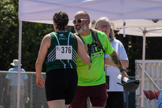 An athletics athlete high fives her coach at a competition.