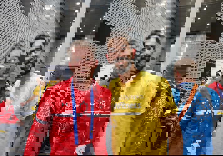 Two men standing beside each other staring into the camera. One is in Special Olypmics Team Canada gear, the other is in a yelow FUNFitness t-shirt.