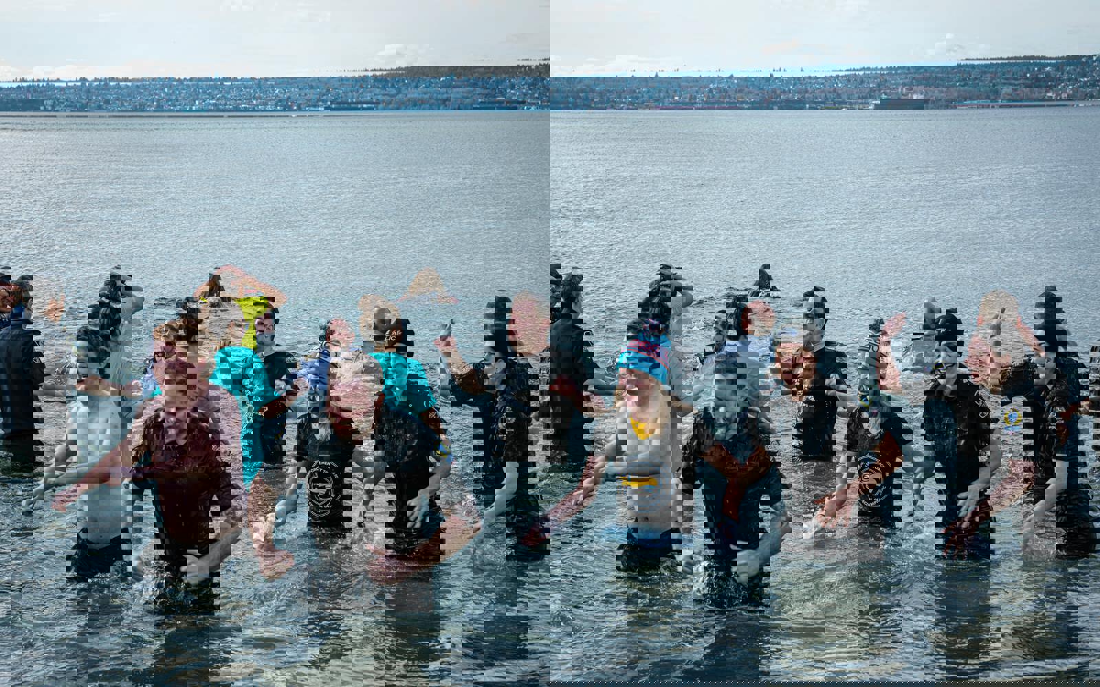 A large group of Law Enforcement Torch Run Polar Plunge participants wade out of the frigid waters with smiles on their faces.