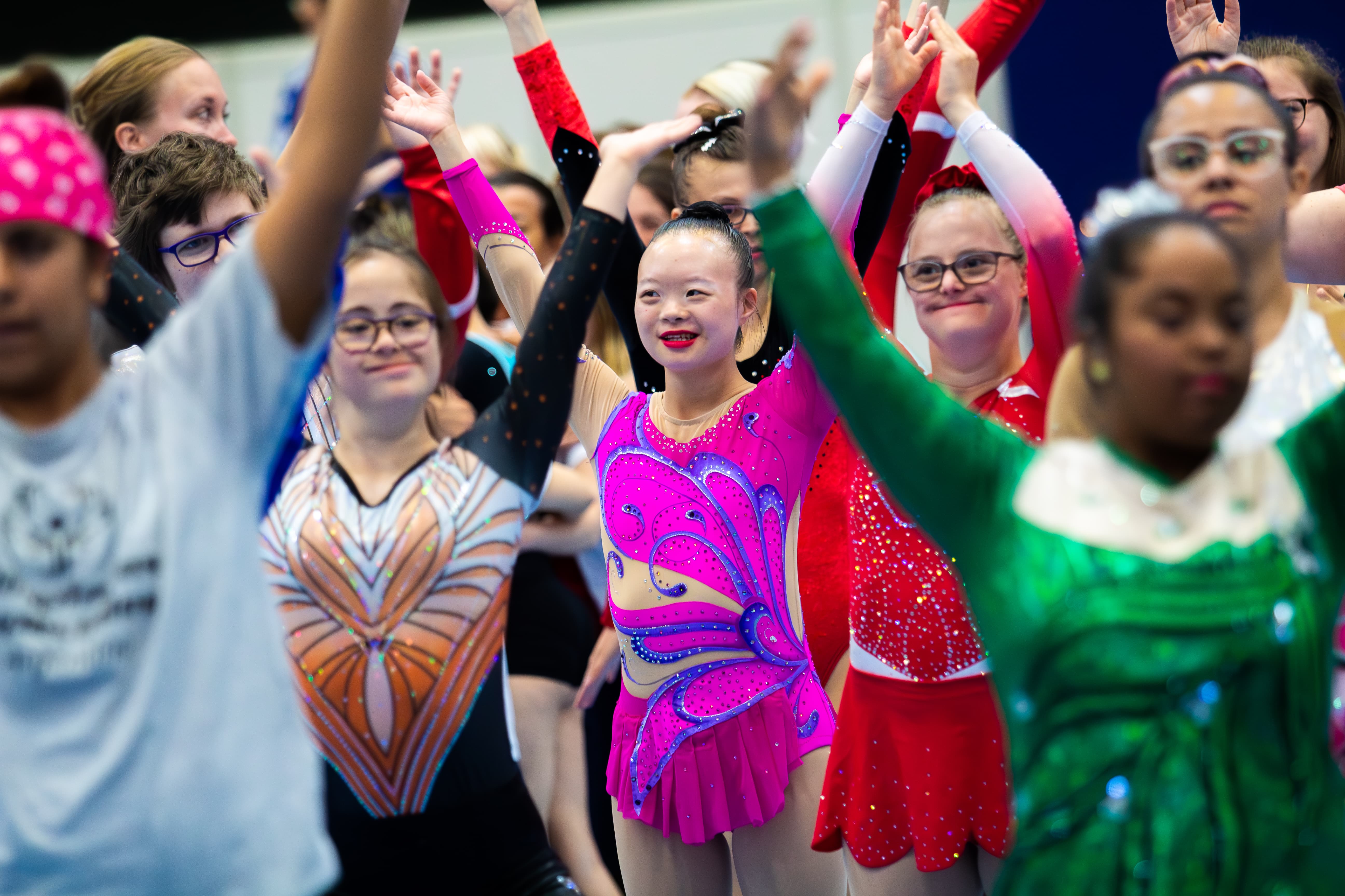 Group of athletes with arms in the air. All are smiling and wearing figure skating costumes Group of athletes with arms in the air. All are smiling and wearing figure skating costumes
