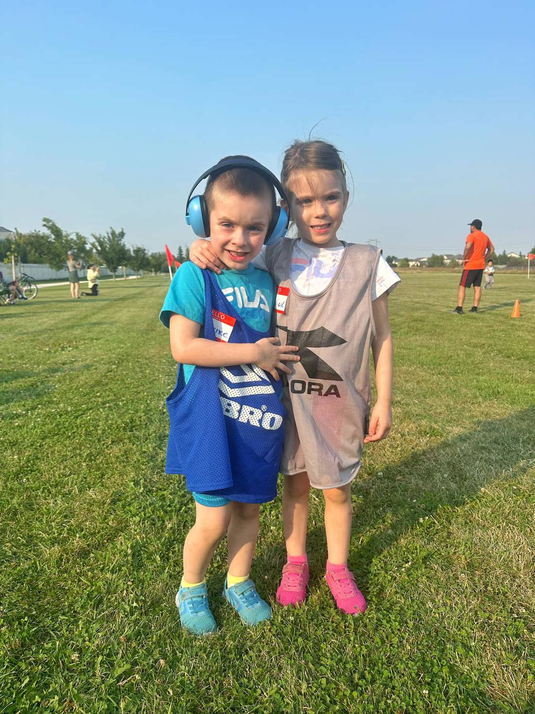Lawrence and Maverick Von Doelln in sport pinnies standing together on a grassy field. 