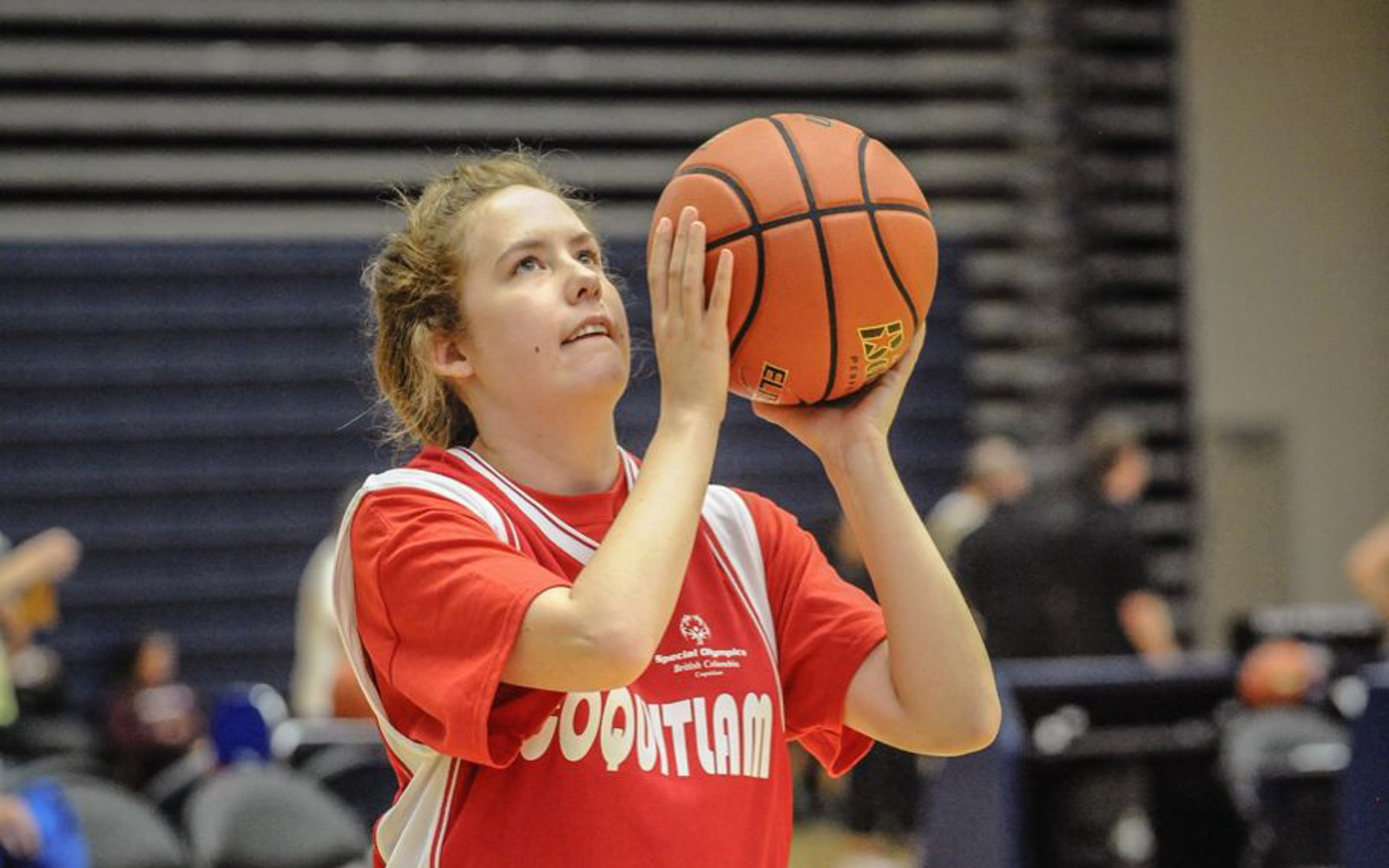 Special Olympics BC basketball athlete with ball poised looks up towards the basket with determination.