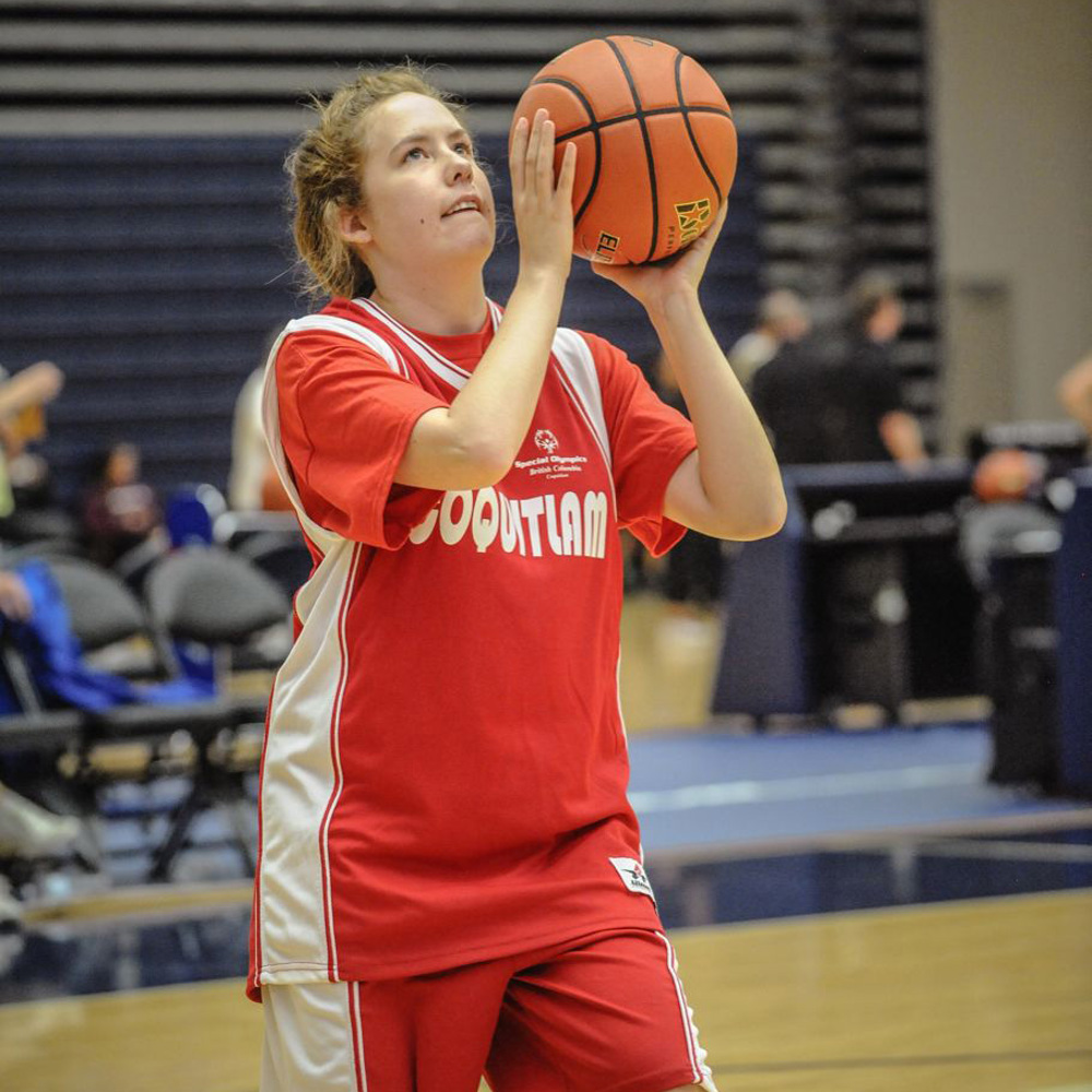Special Olympics BC basketball athlete with ball poised looks up towards the basket with determination.