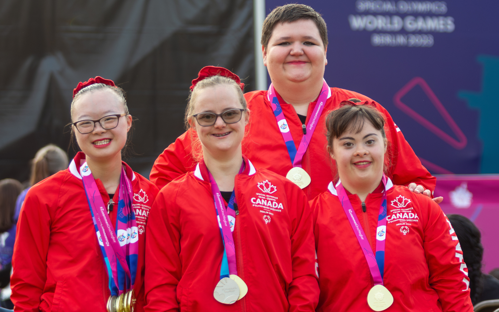 Quatre athlètes vêtus de l'uniforme de l'équipe canadienne, une médaille autour du cou.