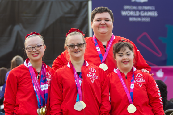 Four athletes in Team Canada uniforms with medals around their necks. 