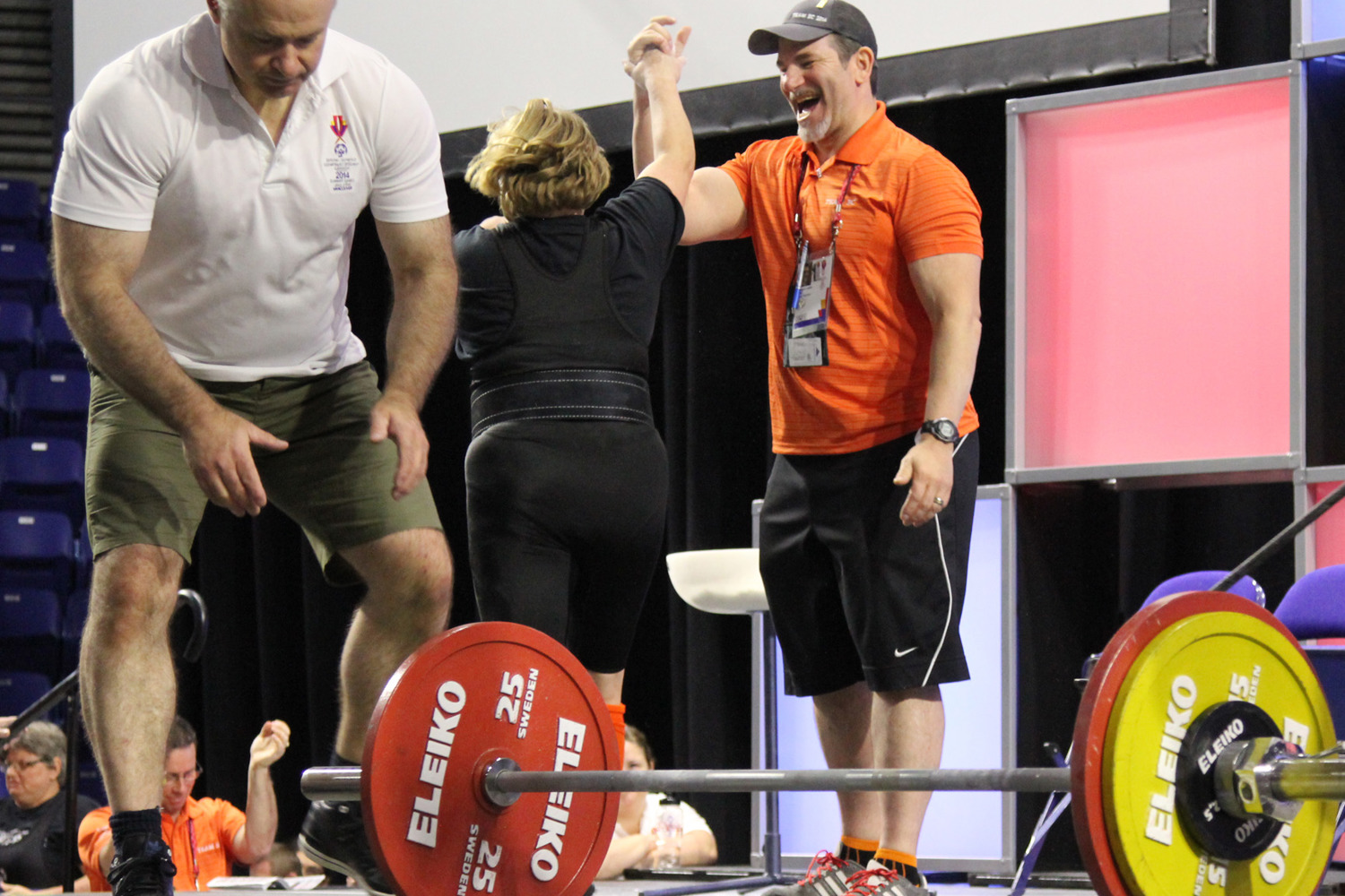 A powerlifting athlete and her coach high five each other after a good lift at a competition.