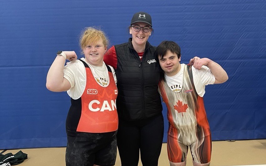 2 Special Olympics Powerlifting athletes with their Coach at a competition
