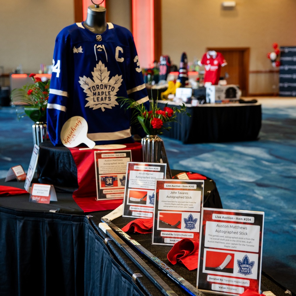 Items on display at a charity auction, including hockey sticks and a jersey