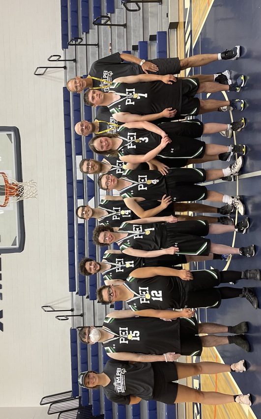 A Special Olympics Basketball team stands under the net, wearing their gold medals