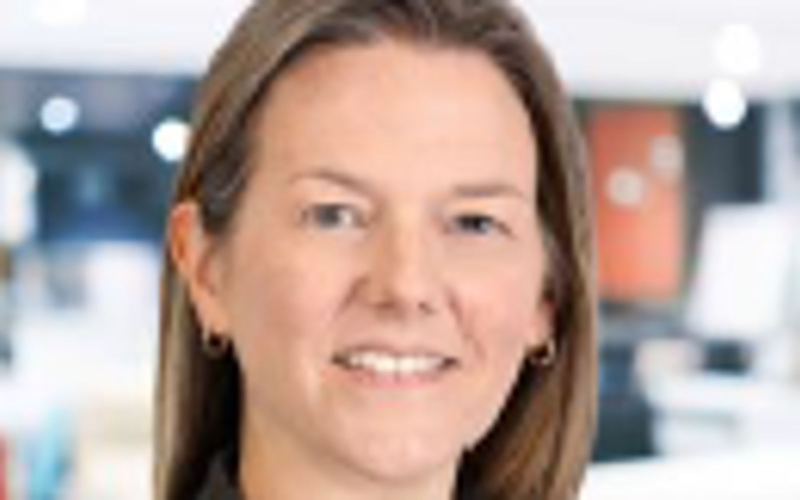 Femme aux longs cheveux blonds portant une chemise blanche et un blazer noir.