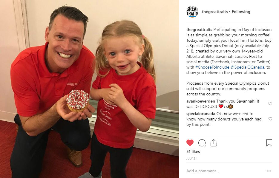 Mark Tewskbury holds a Special Olympics Donut with 6-year-old athlete Alma.
