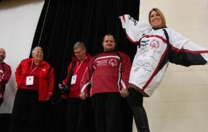 Representative from middle school poses in signed jersey from Special Olympics Ontario floor hockey team.