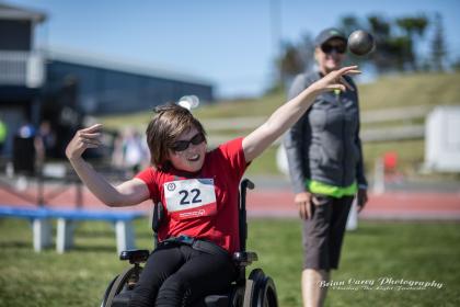 Athlete in wheelchair throwing a shot put ball.