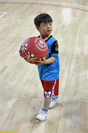 A young Special Olympics athlete holds a ball.
