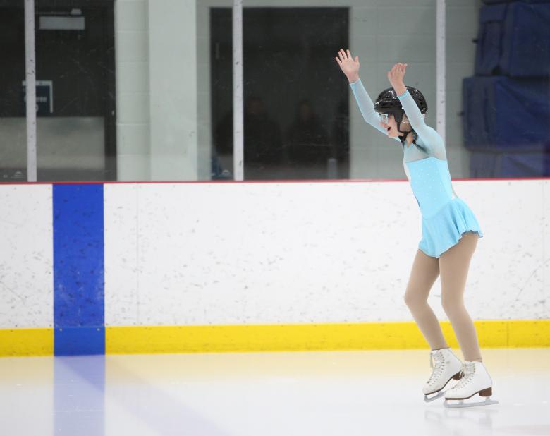 Moriah on the ice with her arms up