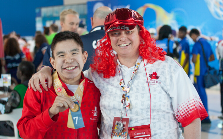 A coach poses for a photo with her arm around an athlete