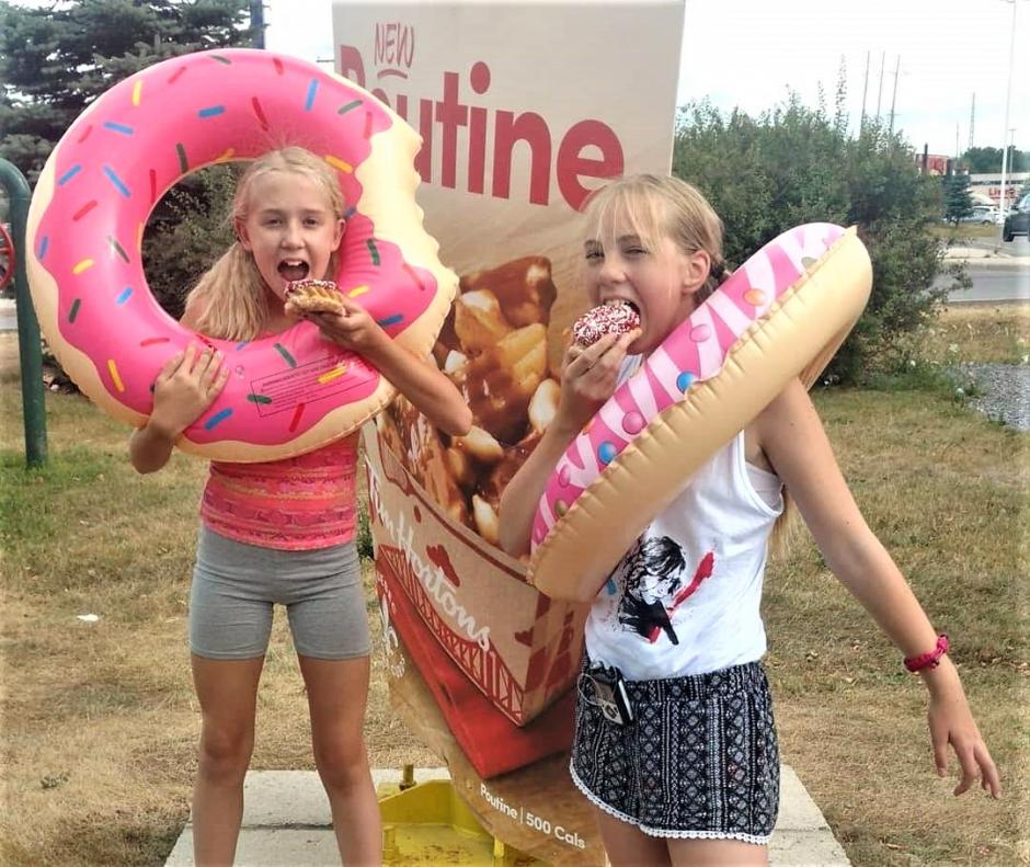 Gemma from Ontario poses with a friend with Special Olympics Donuts and donut floaties around their waist