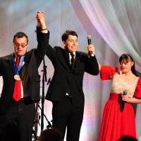 Matthew Williams on stage in formal dress with two fellow athletes