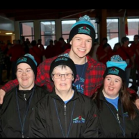Logan Wilson poses for a photo with his arms around Special Olympics athletes.