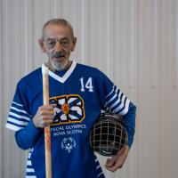 Richard Myette poses with his floor hockey stick looking into the camera