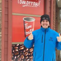 Athlete Jesse Renouf smiling and standing in front of a Tim Hortons