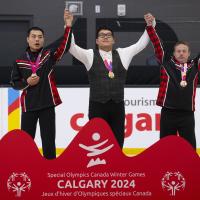Alexander Pang standing on podium raising his hands with two other athletes
