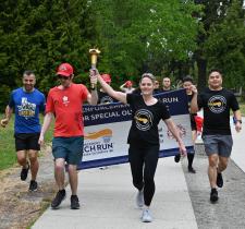 Law enforcement members and SOBC athletes running with LETR banner and torch
