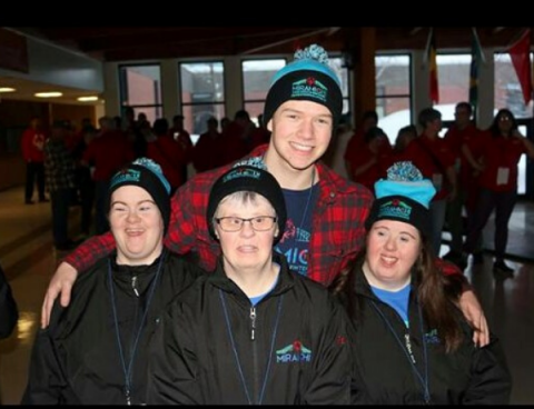 Logan poses for a photo with his arms around Special Olympics athletes.